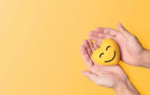 Hands holding a smiling heart